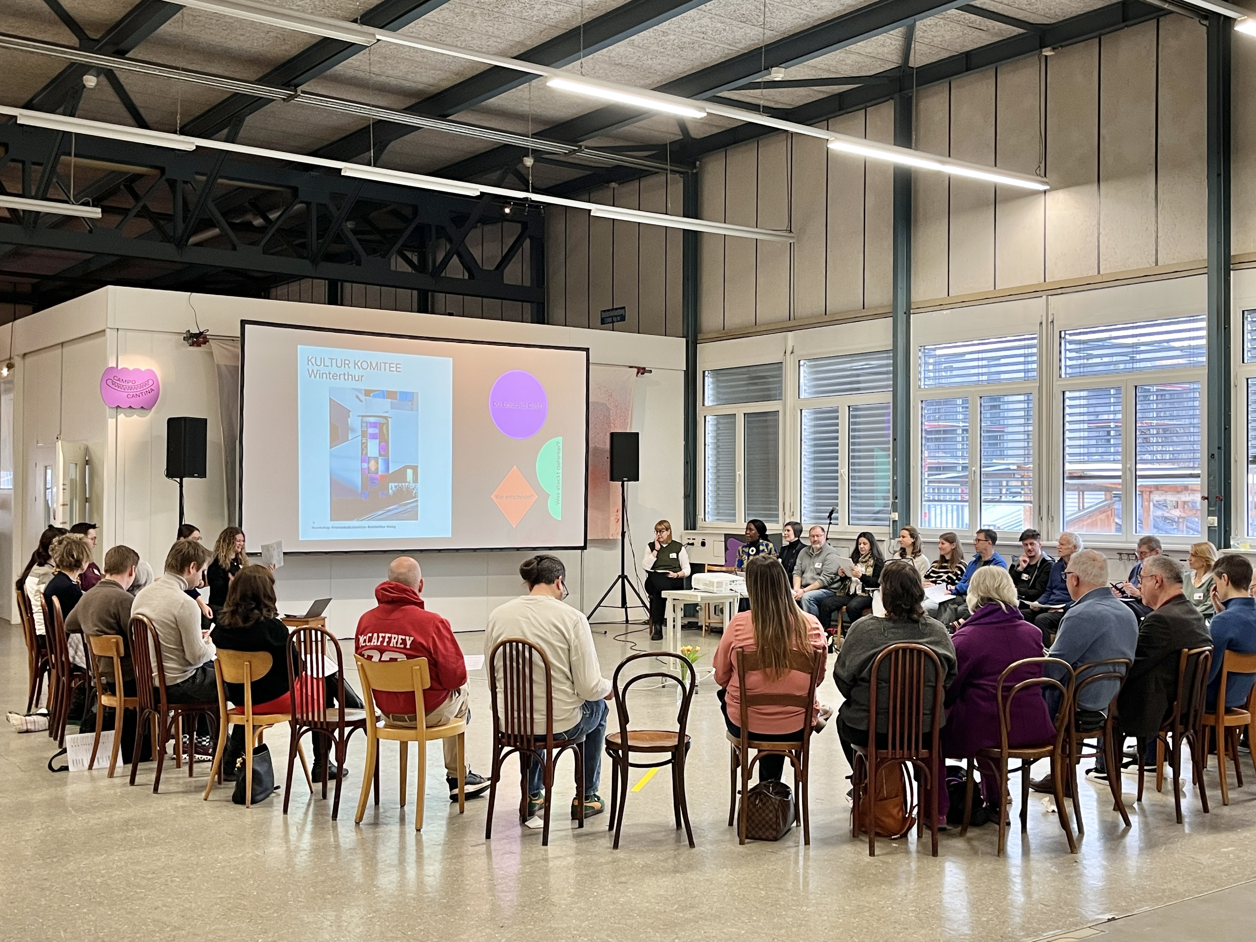 Kultur Komitee participants seated in a circle, with the Winterthur programme on the screen